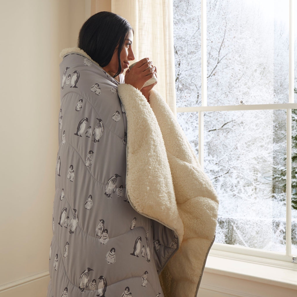 Night Lark®  Cosy Sherpa Throw Winter Penguins on a model drinking brew